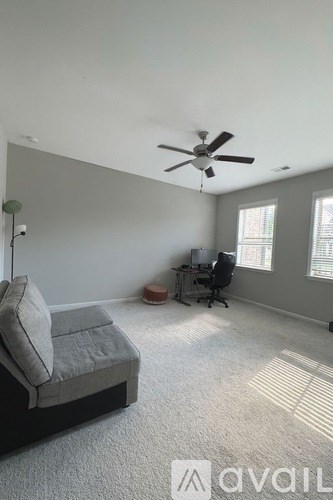 A room with a ceiling fan and a bed.