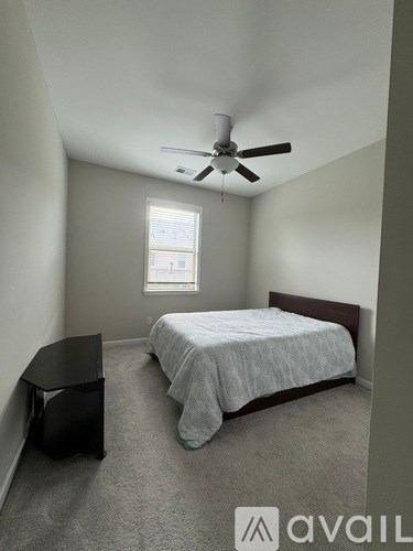 A bedroom with a bed, a ceiling fan, and a window.