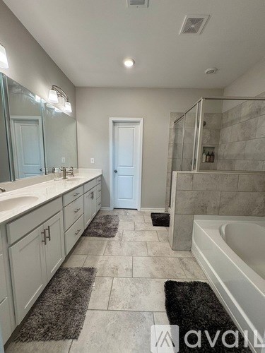 A bathroom with a white tub, sink, and mirror.
