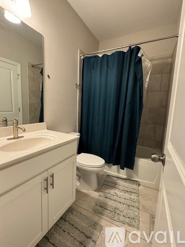 A bathroom with a white sink, a toilet, and a blue shower curtain.