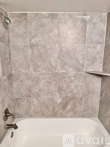A bathroom with a tub and tiled walls.