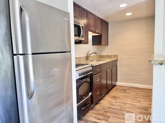 A kitchen with a stainless steel refrigerator and wooden cabinets.
