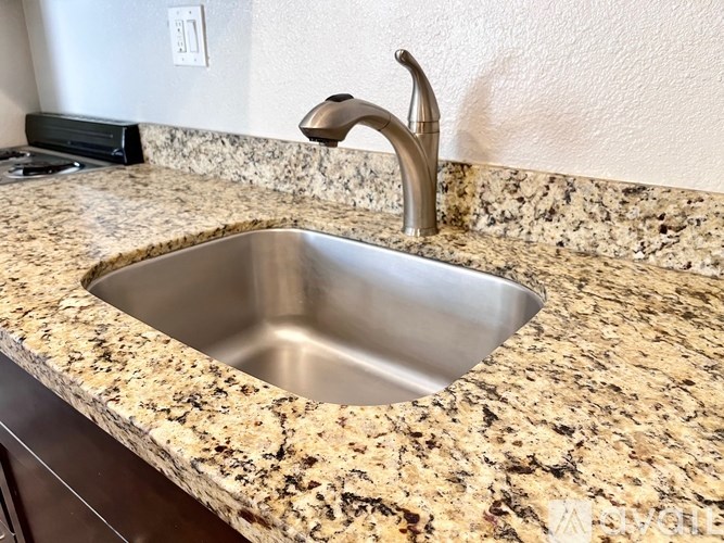A stainless steel sink is installed in a granite countertop.