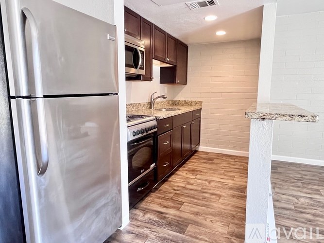 A kitchen with a stainless steel refrigerator and wooden cabinets.