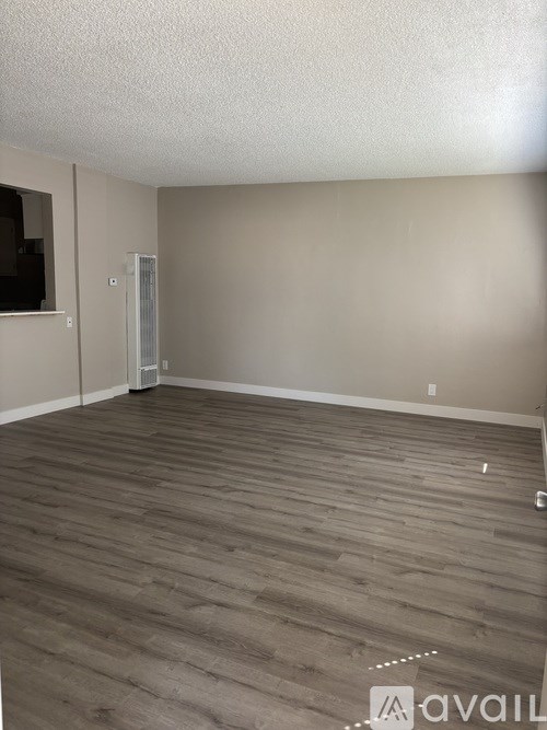 A room with wooden flooring and a wall-mounted TV.