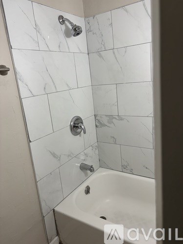 A white bathroom with a marble tile shower.