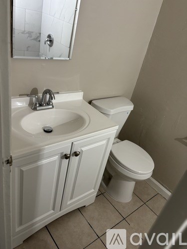 A bathroom with a sink, toilet and cabinet.