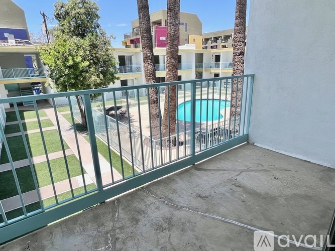 A balcony with a pool and palm trees in the background.