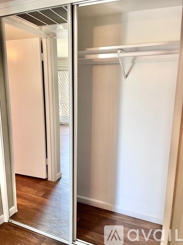 A white door is open to a room with a white wall and a wooden floor.