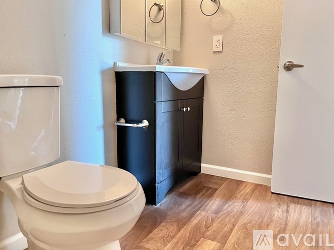A white toilet sits next to a black trash can in a small bathroom.