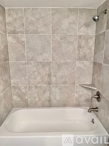 A white bathtub with a shower head and faucet.