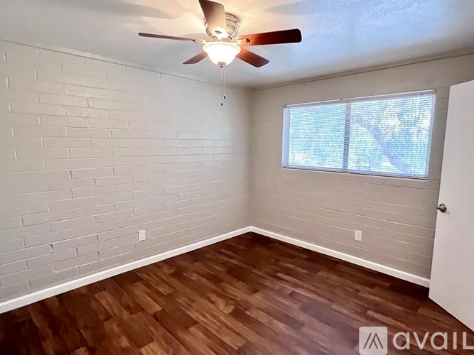 A room with a ceiling fan and wooden flooring.