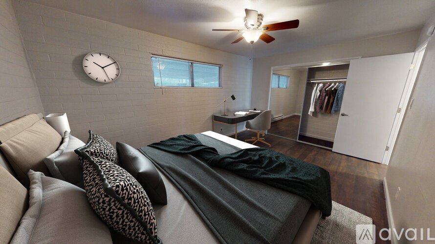 A bedroom with a bed, couch, and a clock on the wall.