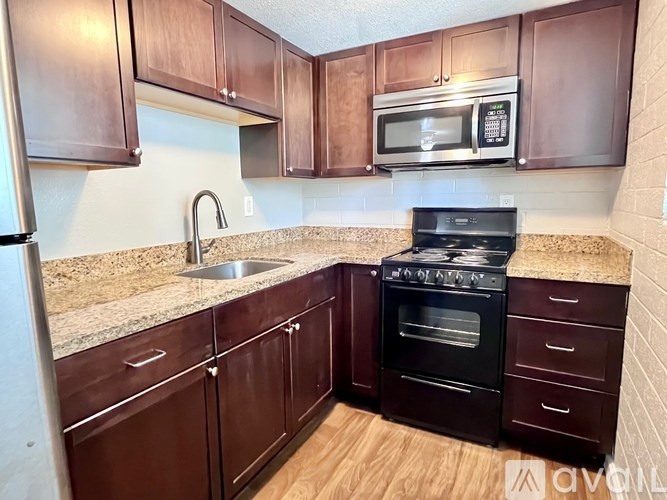 A kitchen with brown cabinets and a black stove top oven.