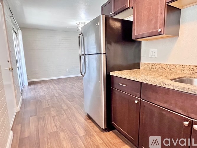 A kitchen with a black refrigerator and brown cabinets.