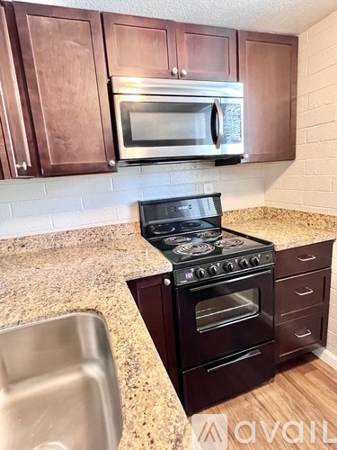 A kitchen with a black stove top oven and microwave above it.