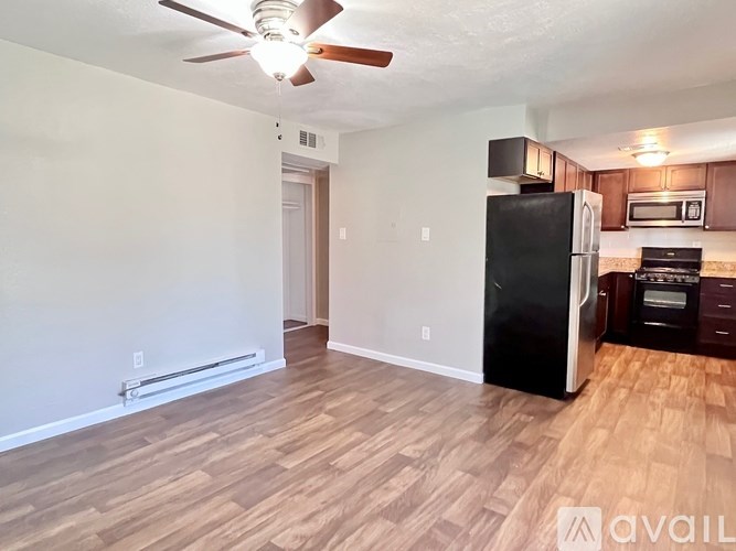 A kitchen with a black fridge and wooden floors.