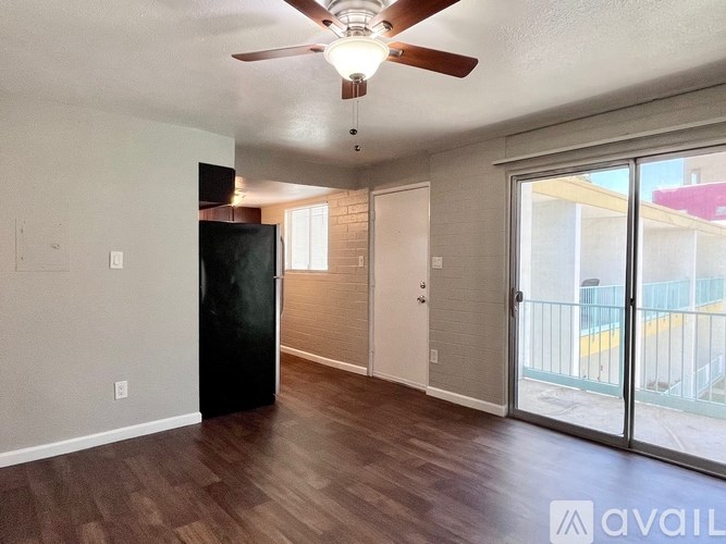 A room with a ceiling fan and sliding glass doors.