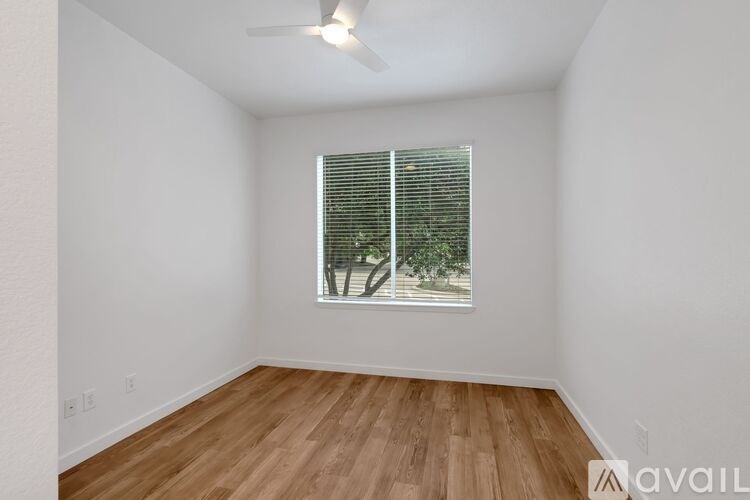 A room with wooden flooring and a window with blinds.