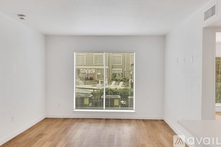 A room with a large window and wooden flooring.