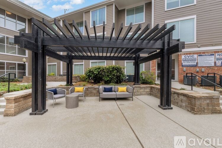 A patio area with a pergola and seating area in front of a building.