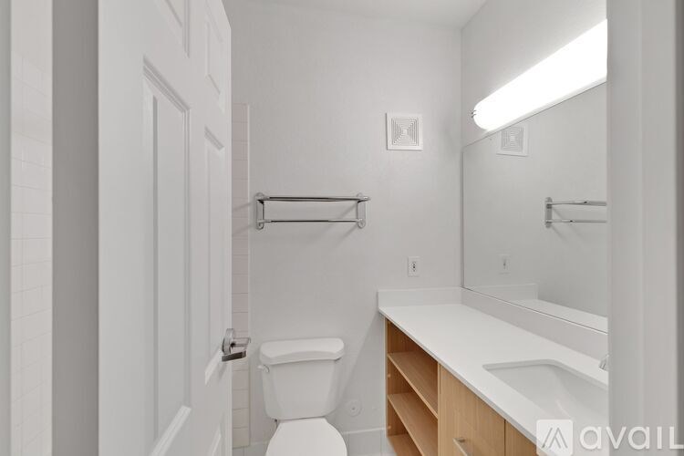 A white bathroom with a toilet, sink, and mirror.