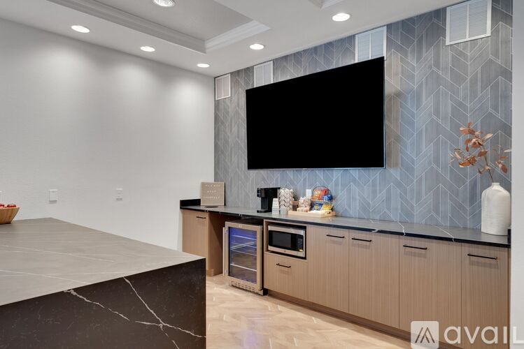 A modern kitchen with a large island and a flat screen TV mounted above it.