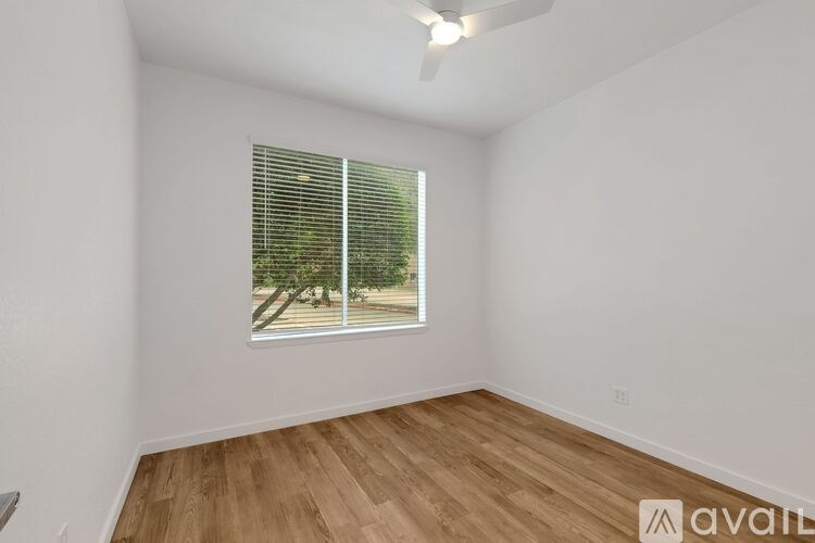A room with wooden flooring and a window with blinds.