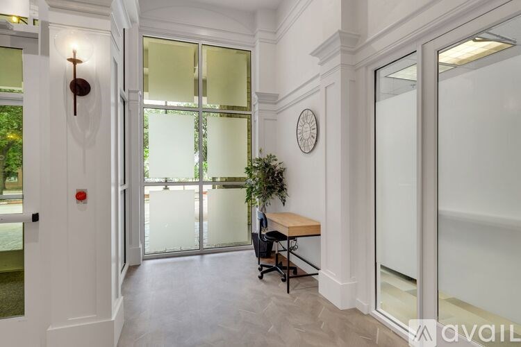 A room with a desk and a plant in a window.