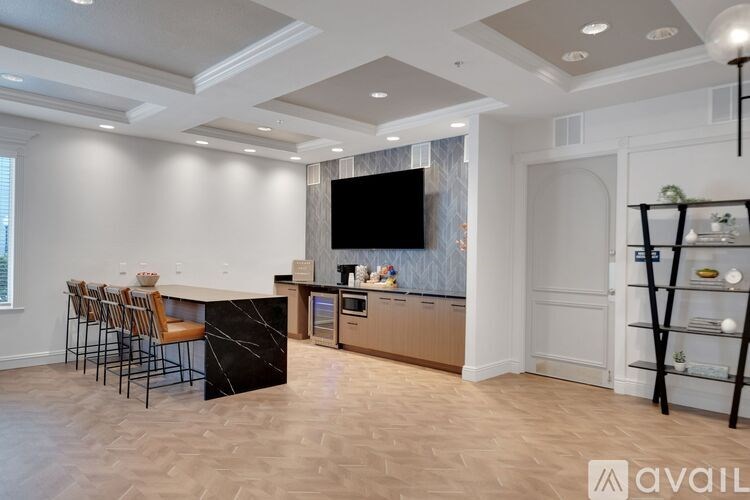 A modern kitchen with a bar area and a television mounted on the wall.
