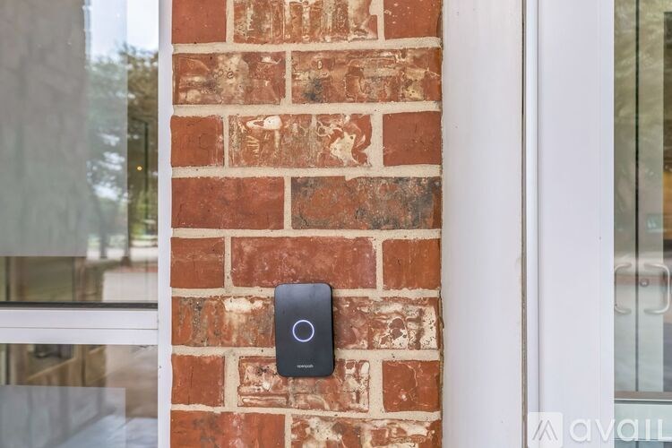 A black smart device is mounted on a brick wall.