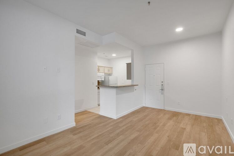 A spacious room with wooden flooring and white walls.