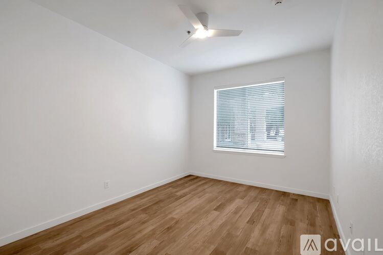 Empty room with wooden floor and a window with blinds.