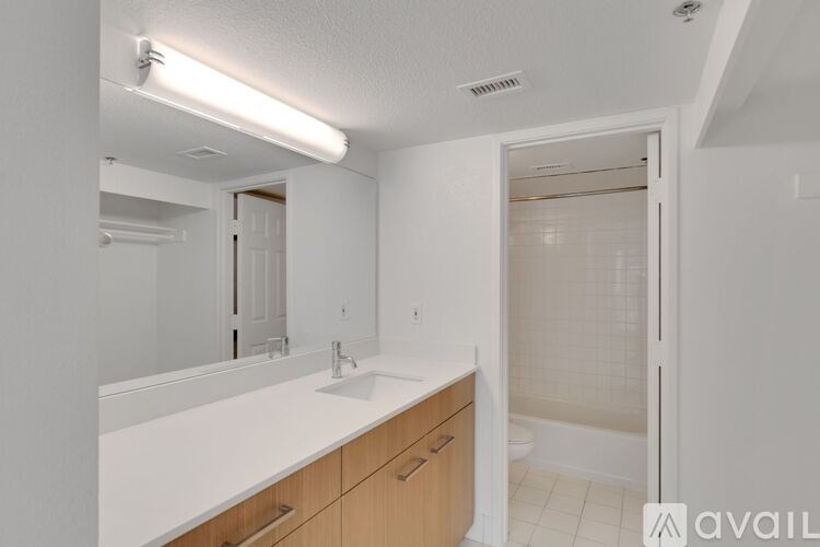 A bathroom with a sink, mirror, and shower.