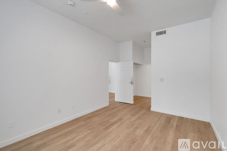 A room with wooden flooring and white walls, with a door on the right side.
