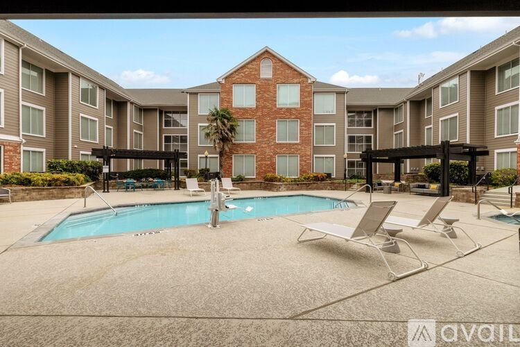 A large apartment complex with a pool and lounge chairs.