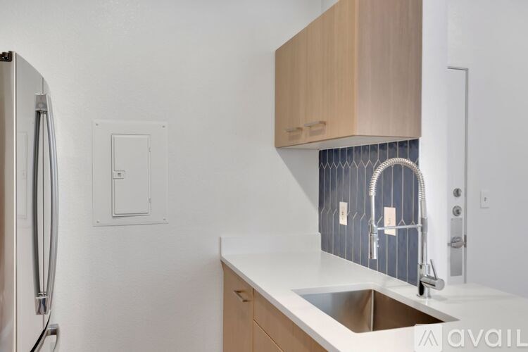 A kitchen with a refrigerator, sink, and cabinets.