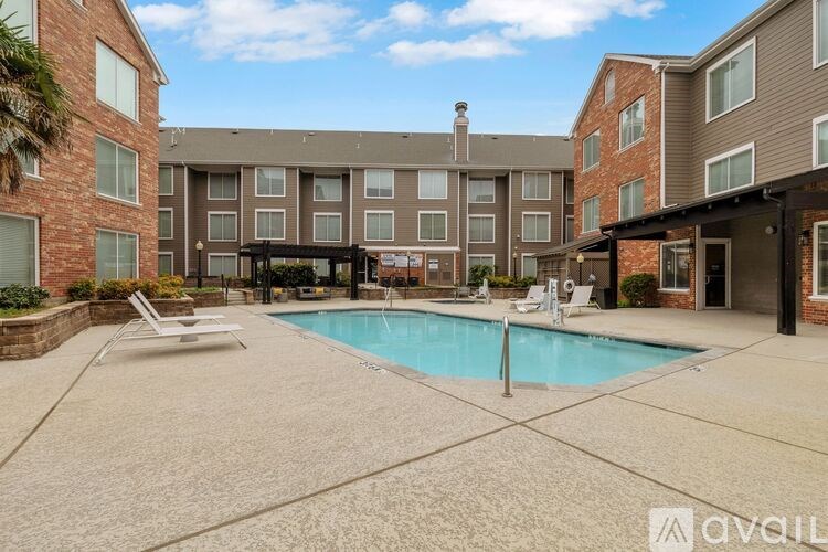 A large outdoor swimming pool surrounded by a concrete patio and lounge chairs.