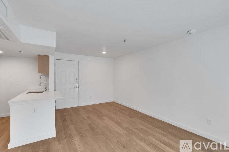 A white kitchen island with a sink and a cabinet is in a room with wooden flooring and white walls.