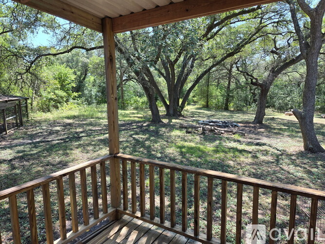 A wooden deck overlooks a grassy area with trees.