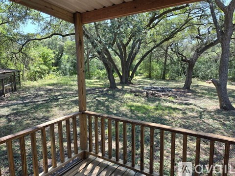 A wooden deck overlooks a grassy area with trees.
