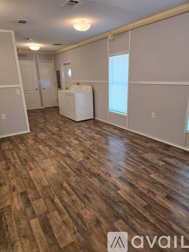 A room with wooden flooring and a washer and dryer in it.
