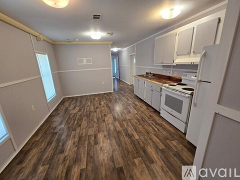 A kitchen with white appliances and wooden floors.