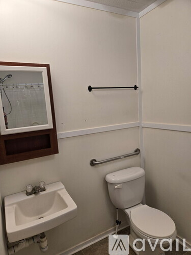 A white toilet sits next to a white sink in a small bathroom.