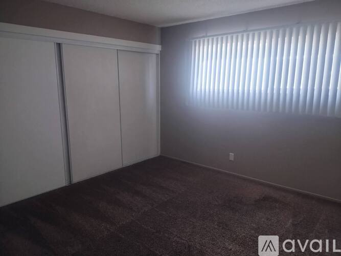 A room with a carpeted floor and a window with blinds.