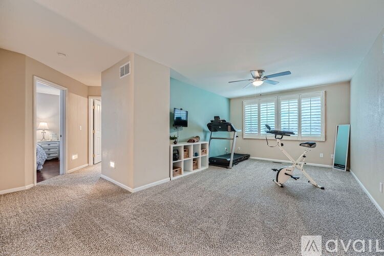 A spacious room with a treadmill and a fan.