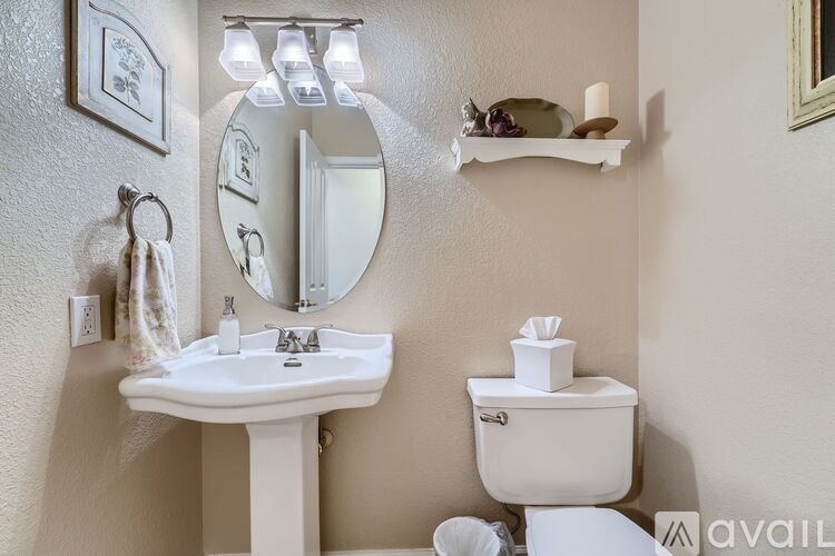 A bathroom with a sink, toilet, mirror, and shelf.