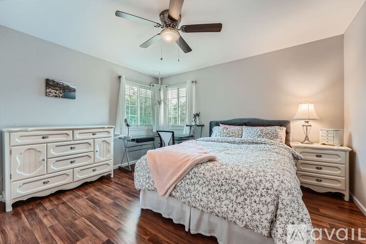 A bedroom with a bed, dresser, and desk with a ceiling fan.