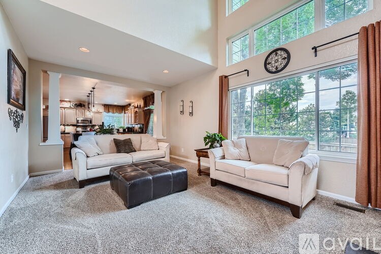 A living room with a white couch and a black ottoman.