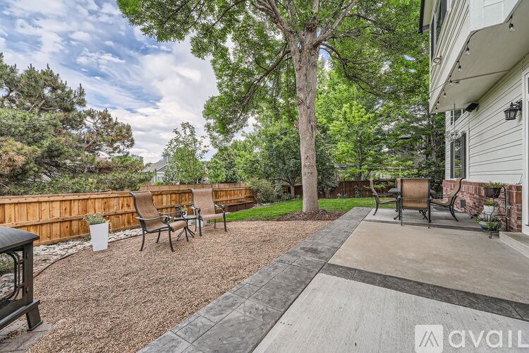 A backyard with a wooden fence, a tree, and a patio furniture set.